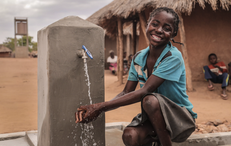 Młody chłopiec w Tanzanii cieszy się świeżą wodą dostarczaną przez solarny system pompowania wody zainstalowany w jego wiosce przez Innowacja: Afryka (kliknij, aby powiększyć)