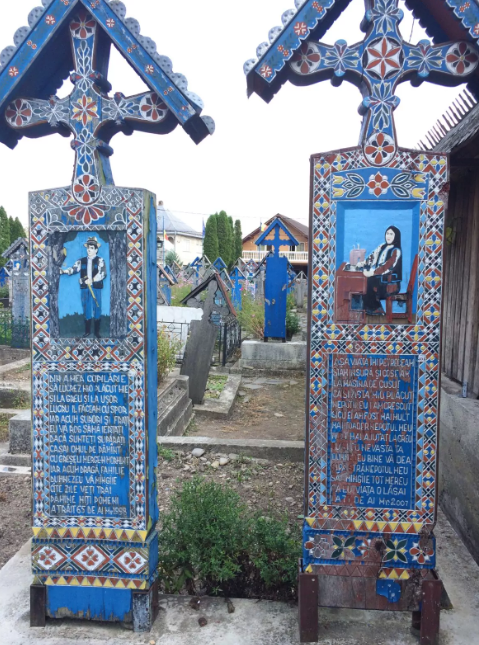 Przykłady drewnianych, jaskrawo malowanych nagrobków na Wesołym Cmentarzu, Săpânța, Rumunia